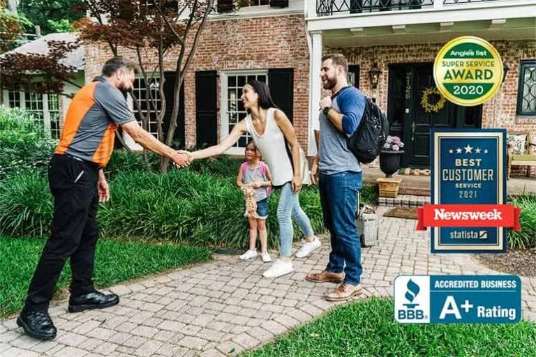 A Marathon Moving crew member shaking hands with a family outside their home, with award badges
